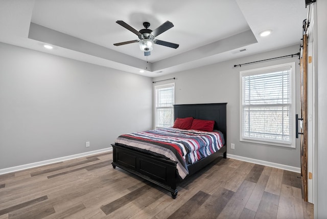 bedroom featuring baseboards, visible vents, wood finished floors, and a raised ceiling
