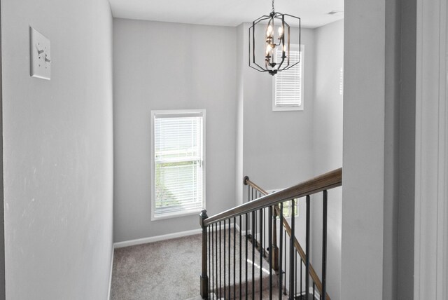 stairway with baseboards, a notable chandelier, and carpet floors