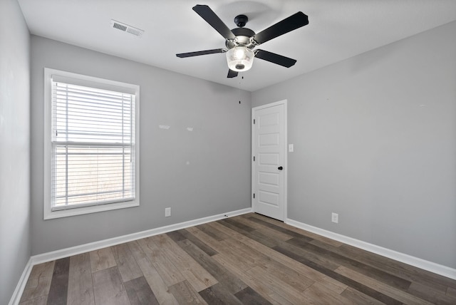 spare room with wood finished floors, baseboards, ceiling fan, and visible vents