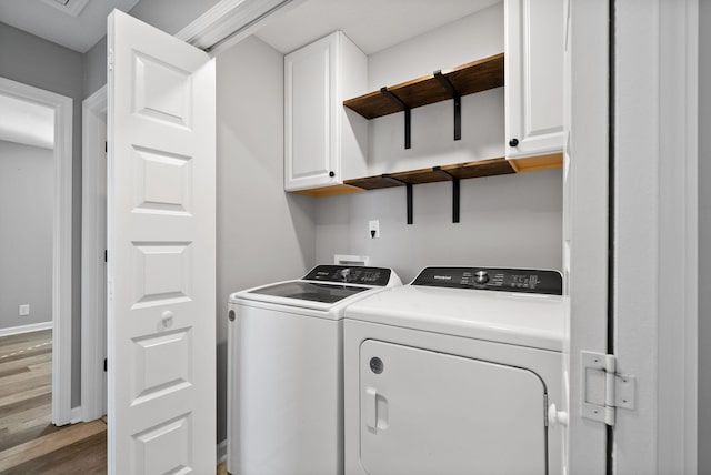 laundry room with independent washer and dryer, cabinet space, baseboards, and wood finished floors