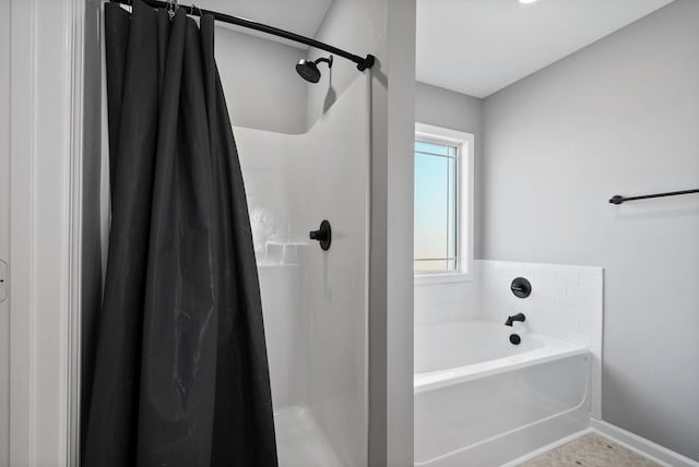 bathroom with baseboards, a garden tub, and a shower stall