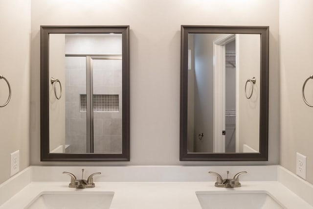 full bathroom featuring a sink, tiled shower, and double vanity