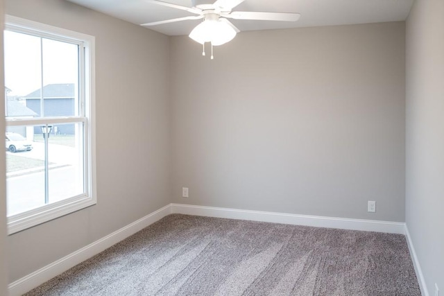 empty room featuring a wealth of natural light, baseboards, and carpet floors