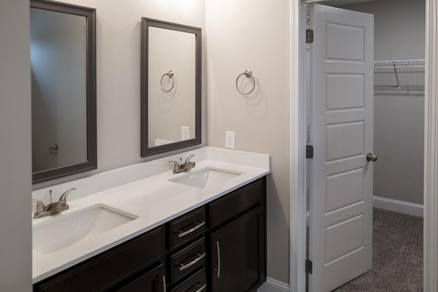 bathroom with double vanity, baseboards, and a sink