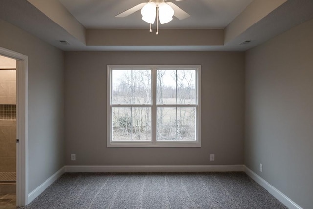 carpeted empty room featuring a raised ceiling, visible vents, baseboards, and ceiling fan