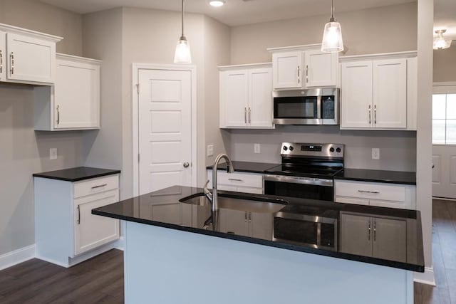 kitchen with dark countertops, white cabinets, appliances with stainless steel finishes, and a sink