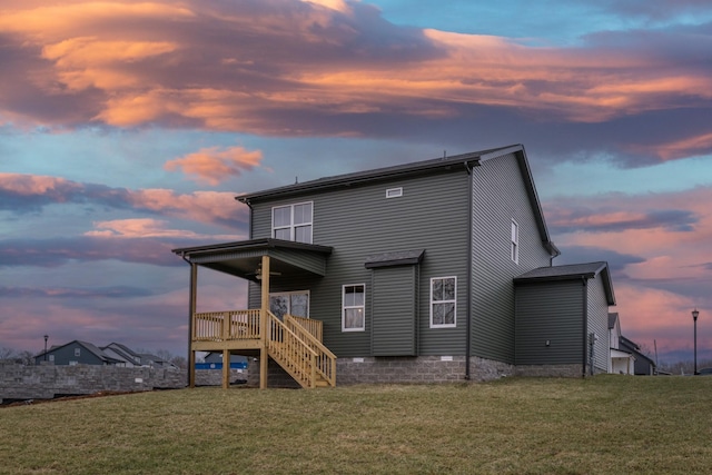 back of house at dusk featuring stairs and a lawn