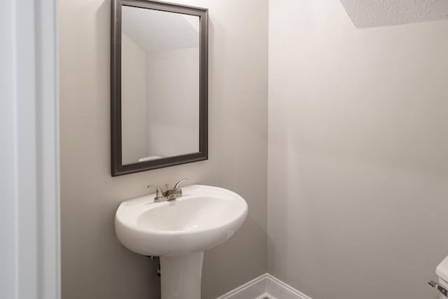 half bathroom with baseboards and a textured ceiling