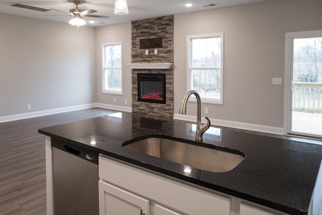 kitchen with visible vents, open floor plan, a stone fireplace, stainless steel dishwasher, and a sink