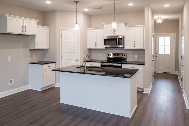 kitchen featuring a sink, dark countertops, dark wood-style floors, and stainless steel appliances