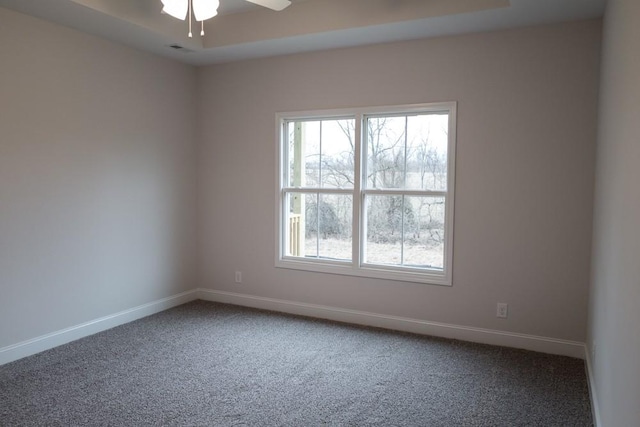 carpeted spare room with visible vents, a ceiling fan, and baseboards