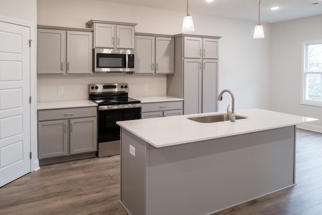 kitchen with dark wood-type flooring, gray cabinetry, pendant lighting, a sink, and stainless steel appliances