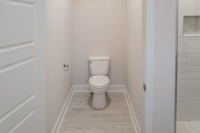 bathroom featuring toilet, wood finished floors, and baseboards