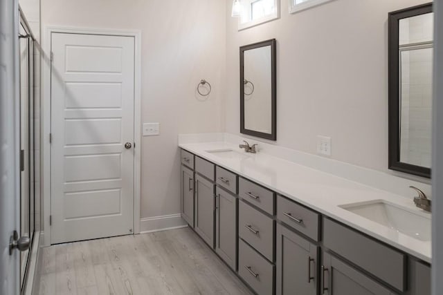 bathroom featuring a shower stall, wood finished floors, and a sink