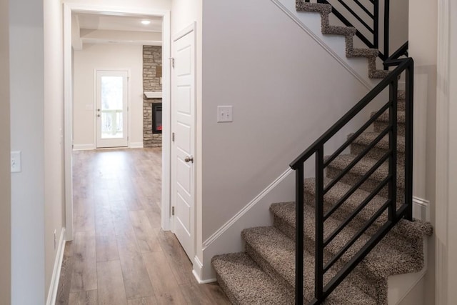 staircase with baseboards, wood finished floors, and a fireplace