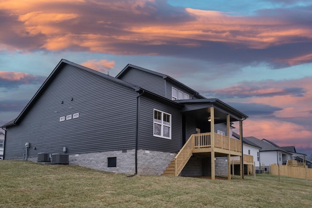 back of house at dusk with stairs, a wooden deck, a yard, and crawl space