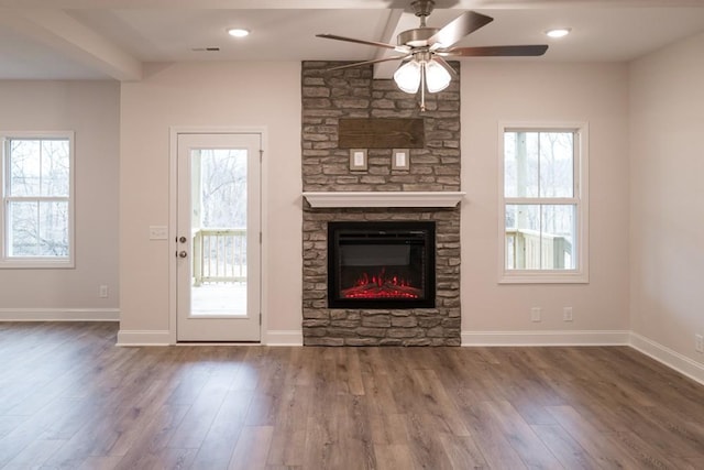 unfurnished living room featuring plenty of natural light, a fireplace, and wood finished floors