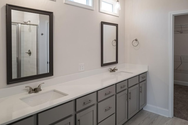 full bath featuring a spacious closet, a shower stall, double vanity, and a sink