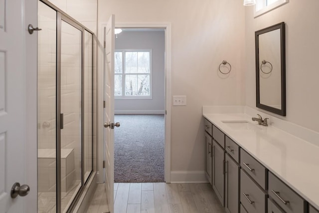 full bathroom featuring wood finished floors, baseboards, a stall shower, and vanity