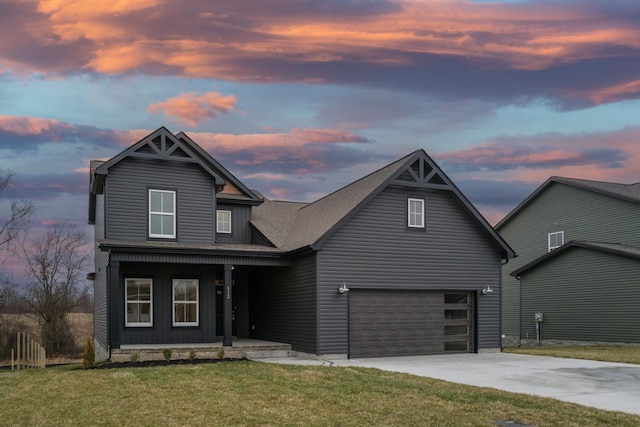 view of front of home with an attached garage, a lawn, covered porch, and driveway