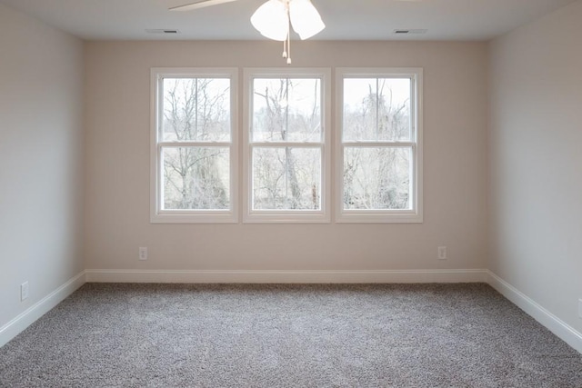 carpeted spare room with visible vents, ceiling fan, and baseboards