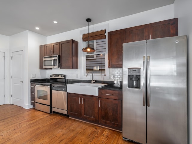 kitchen featuring a sink, tasteful backsplash, wood finished floors, appliances with stainless steel finishes, and dark brown cabinets