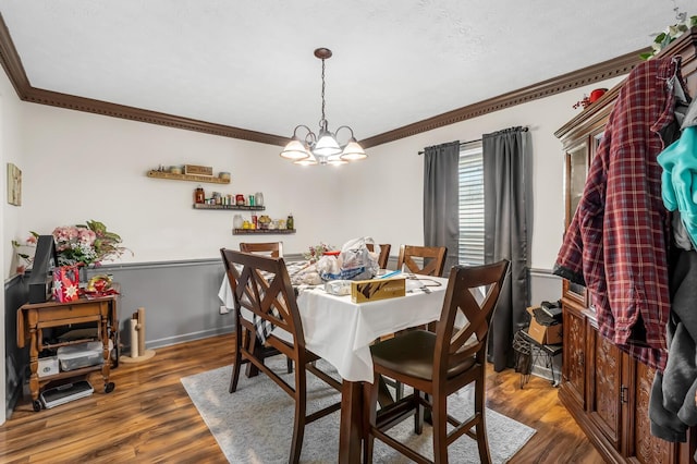 dining area with baseboards, an inviting chandelier, wood finished floors, and crown molding