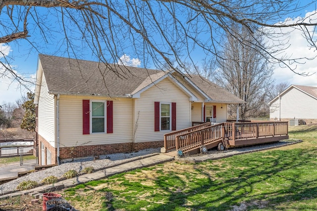 view of front of house with roof with shingles, a deck, a front lawn, and fence