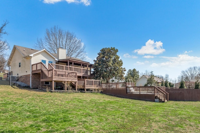 back of property with fence, a chimney, a deck, a lawn, and brick siding