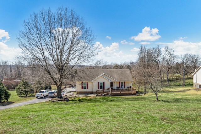 view of front of house with a wooden deck, driveway, and a front yard