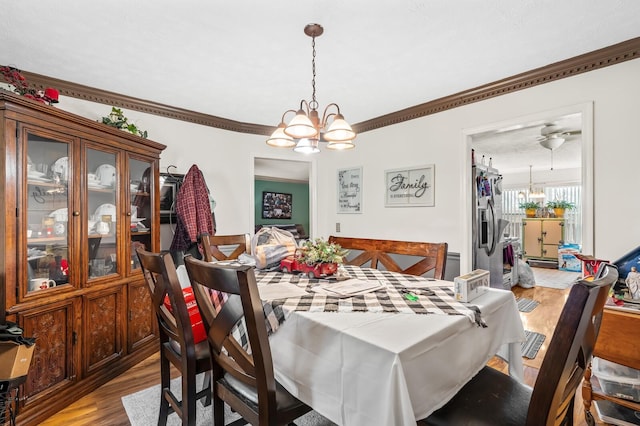 dining room with light wood-style flooring, a chandelier, and crown molding