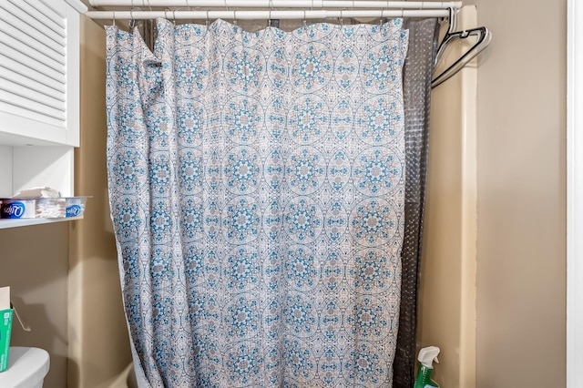 bathroom with a shower with shower curtain and toilet