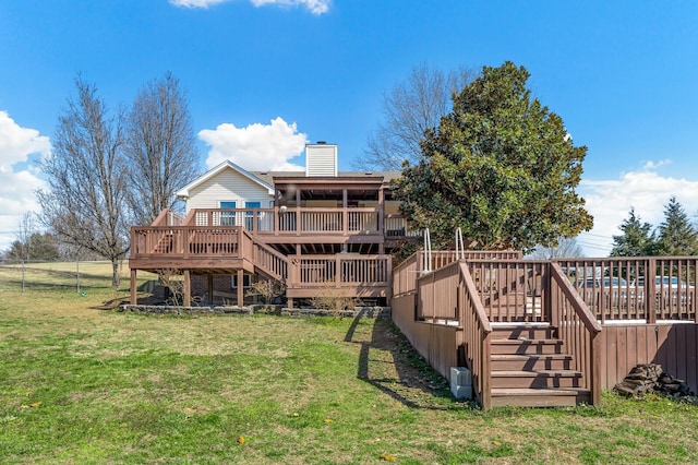 rear view of house with stairs, a deck, a lawn, and a chimney