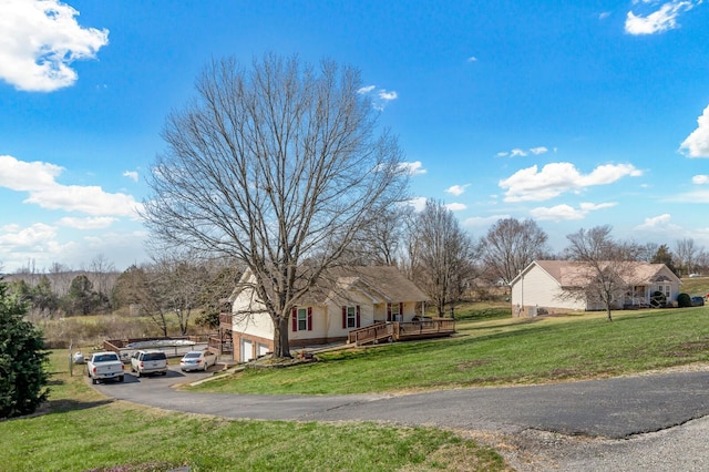 single story home with aphalt driveway, a deck, an attached garage, and a front yard