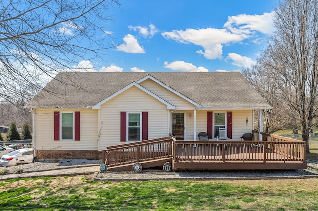 ranch-style home with a front yard, roof with shingles, and a wooden deck