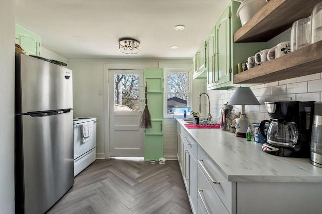 kitchen with a sink, green cabinets, freestanding refrigerator, white electric range oven, and open shelves