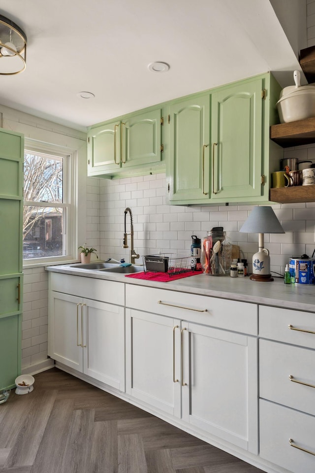 kitchen featuring a sink, tasteful backsplash, green cabinetry, and light countertops