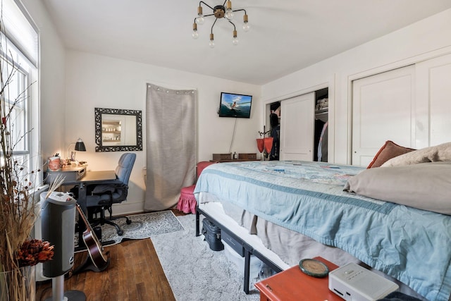 bedroom with a notable chandelier, multiple closets, and wood finished floors