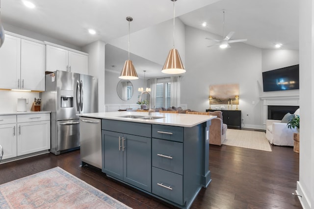 kitchen featuring open floor plan, light countertops, stainless steel appliances, white cabinetry, and a sink