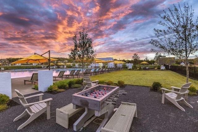 view of property's community with a pool, fence, an outdoor fire pit, a yard, and a patio area