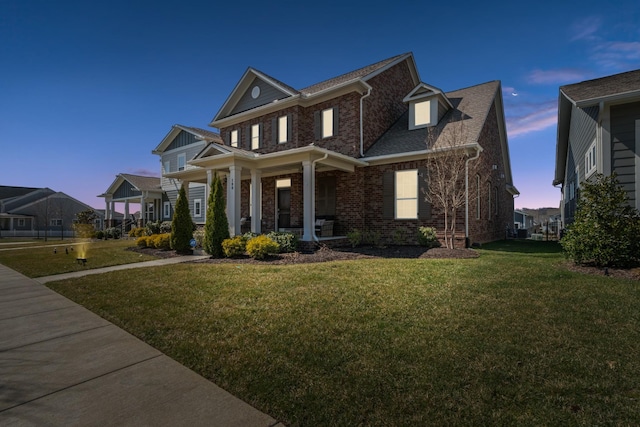 view of front facade featuring brick siding, covered porch, and a front lawn