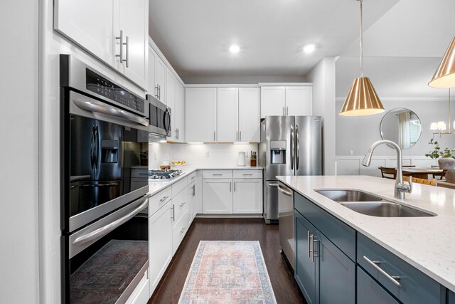 kitchen featuring dark wood finished floors, light stone counters, stainless steel appliances, white cabinetry, and a sink