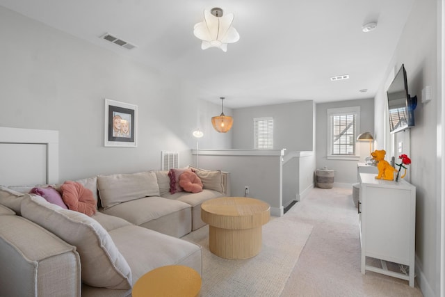 living area featuring visible vents, baseboards, and light colored carpet