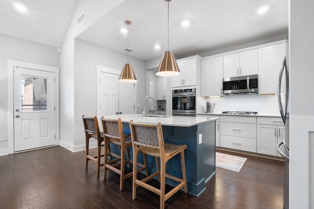 kitchen featuring visible vents, an island with sink, a sink, dark wood-style floors, and stainless steel appliances