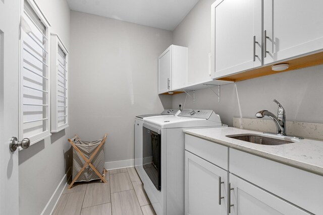 laundry area featuring a sink, baseboards, cabinet space, and separate washer and dryer