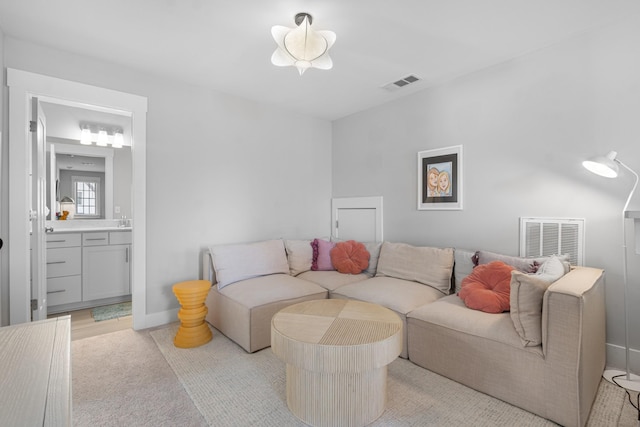 living room featuring baseboards, visible vents, and light carpet