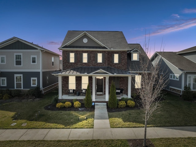 view of front of property with a standing seam roof, a front yard, and covered porch