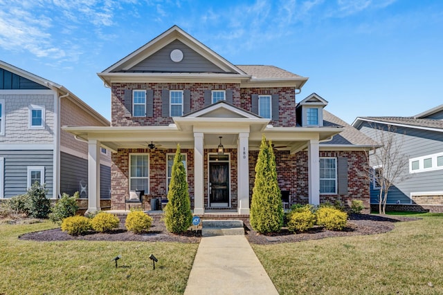 view of front of home with brick siding, a porch, and a front yard