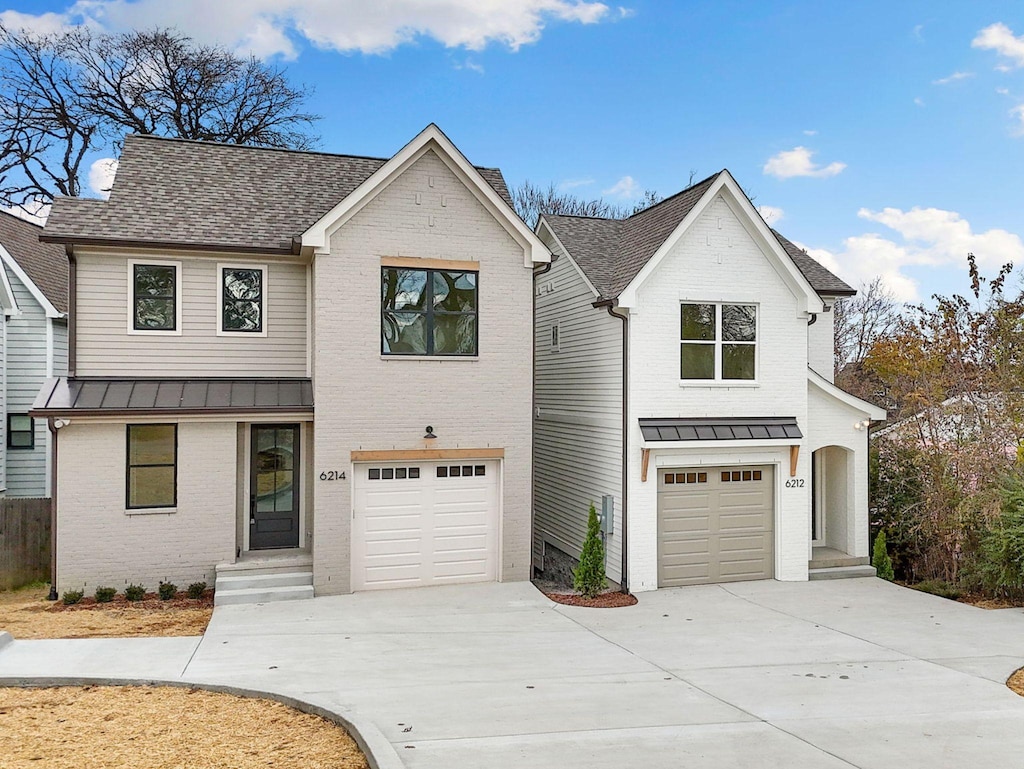 modern farmhouse with a standing seam roof, concrete driveway, an attached garage, and brick siding