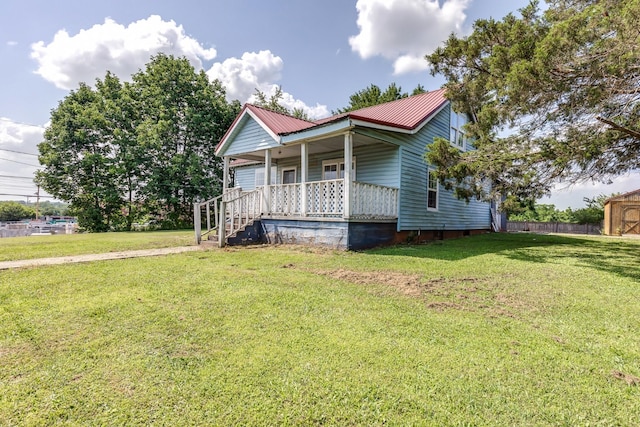 view of front of property with covered porch, metal roof, and a front yard